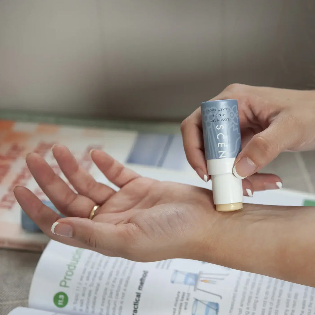 Hand holding a skincare product over an open book